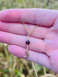 Image 1 of gold crescent moon necklace with red garnet