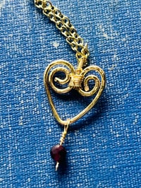 Image 5 of wire wrapped heart with tiny garnet in gold