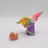 Image 1 of Stewart the gnome with orange flowers and Sage the brown spaniel puppy