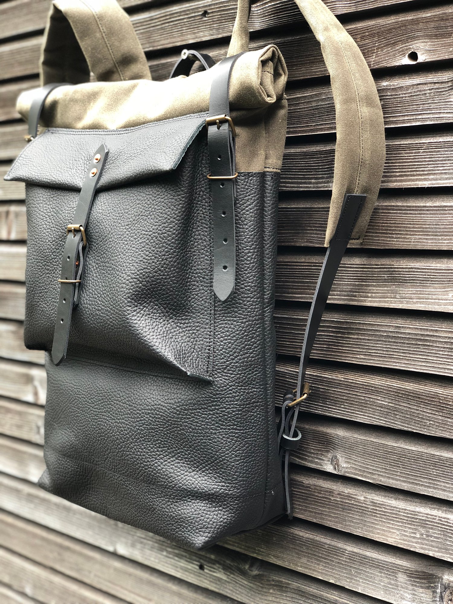Image of Black leather backpack with waxed canvas roll to close top and leather front pocket