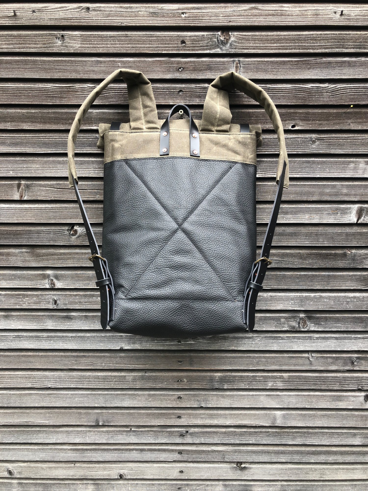 Image of Black leather backpack with waxed canvas roll to close top and leather front pocket