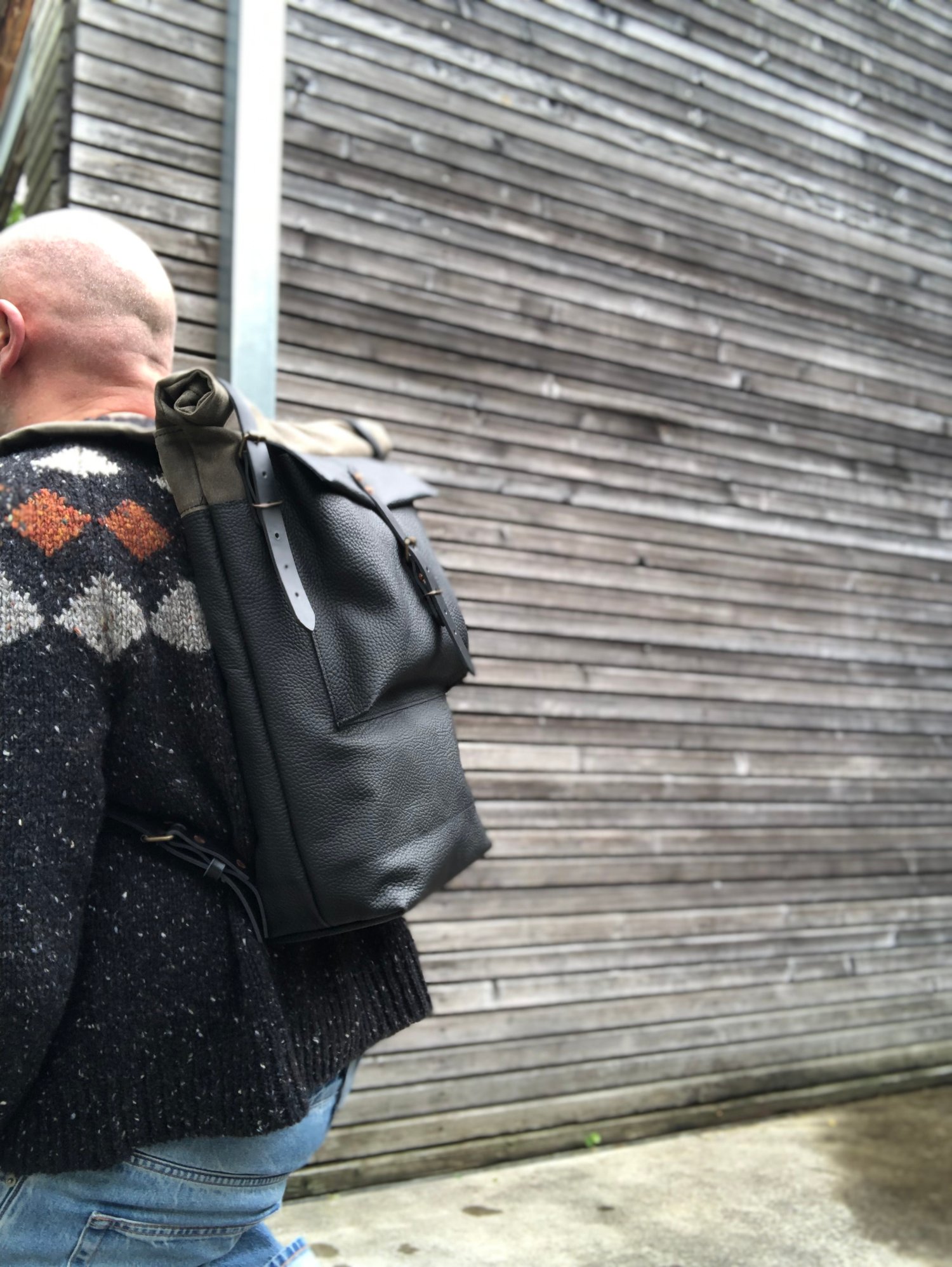 Image of Black leather backpack with waxed canvas roll to close top and leather front pocket