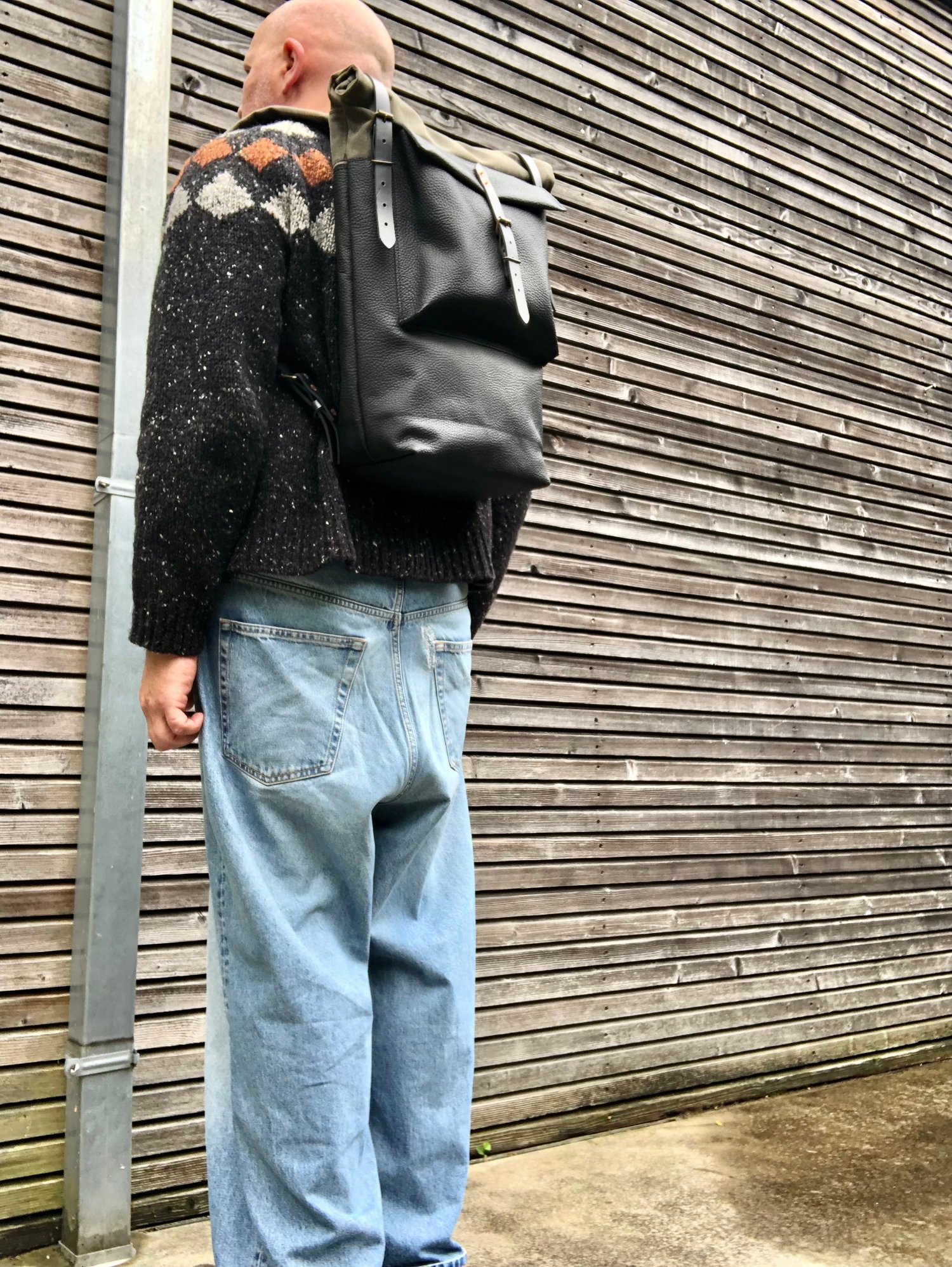 Image of Black leather backpack with waxed canvas roll to close top and leather front pocket