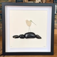 Seaglass bird on polished black pebbles