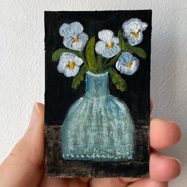 Image of pale violas in an old ink bottle