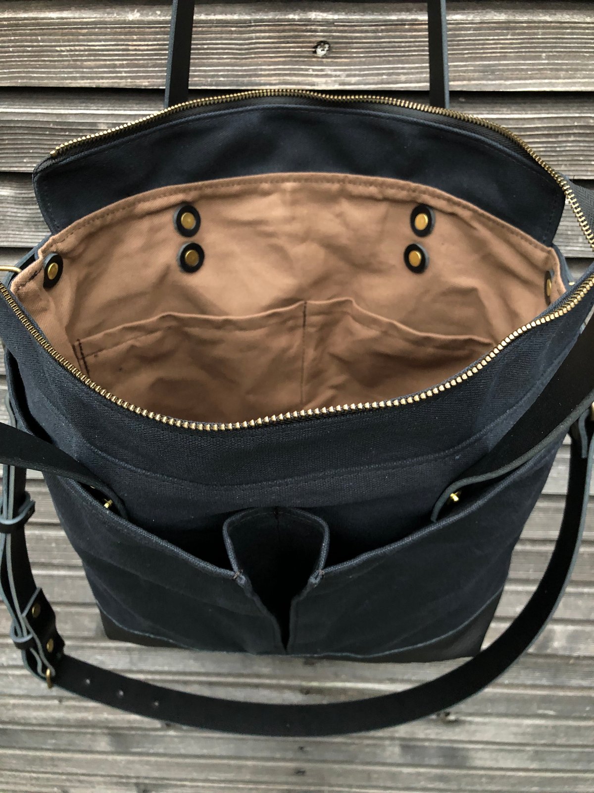 Black waxed canvas tote bag with leather bottom handles and cross