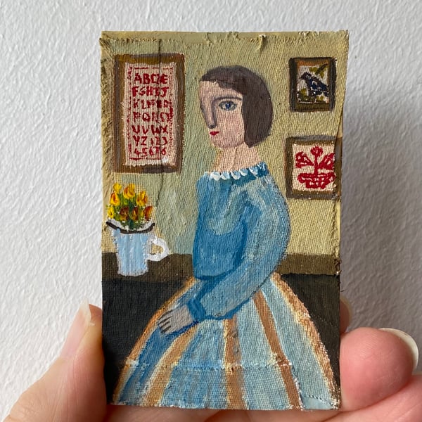 Image of woman in blue  with stitched samplers 