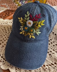 Image 1 of Blue and green hand embroidered flowers on an adjustable dark blue jean fabric hat