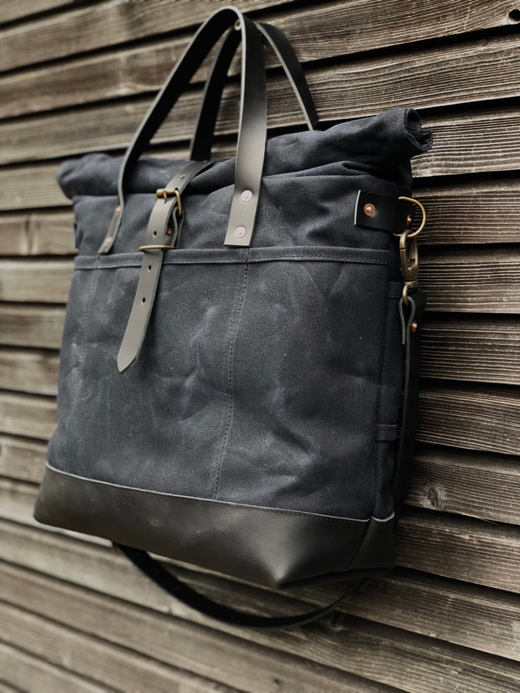 Image of Black waxed canvas carryall with luggage handle attachment leather handles and shoul