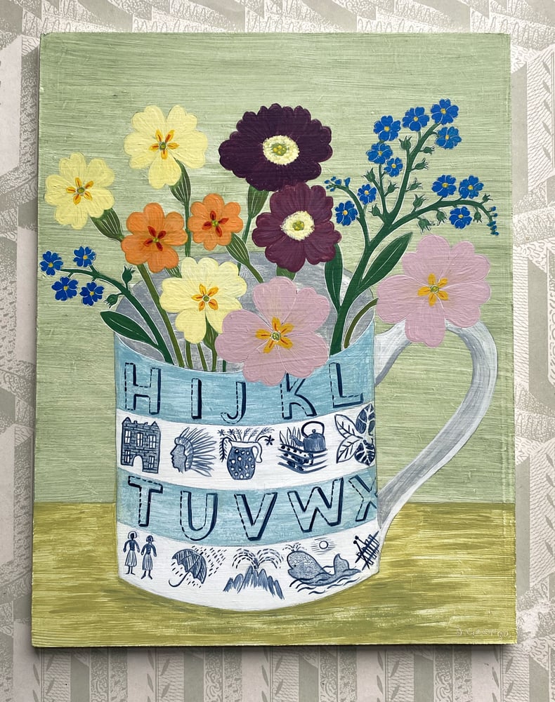 Image of Blue alphabet cup and bright primroses 