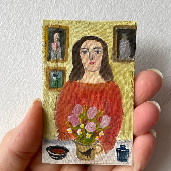 Image of woman at a table with summer flowers and paintings