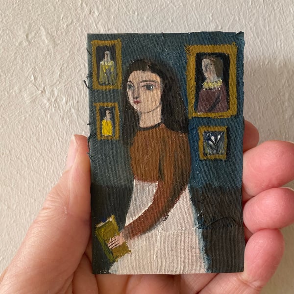 Image of Woman in interior holding a book - tiny painting 