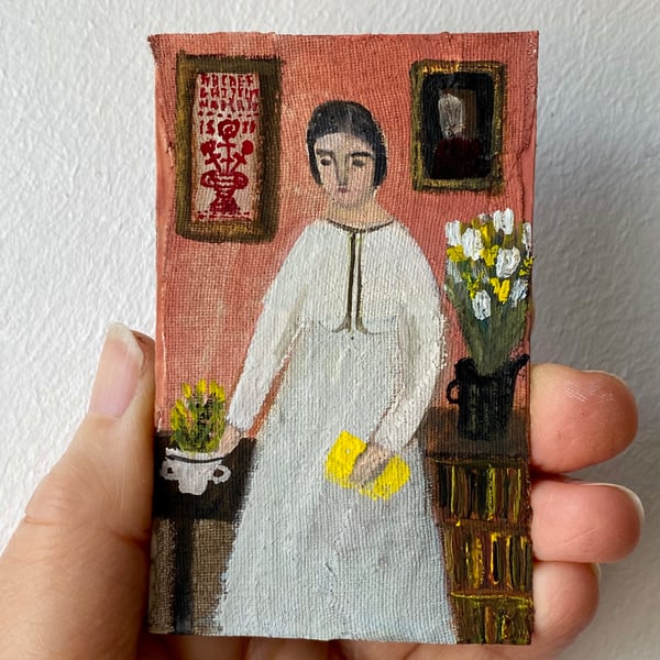 Image of woman with yellow book and sampler on the wall