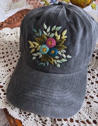 Blue and dark pink hand embroidered flowers on an adjustable dark grey fabric hat 