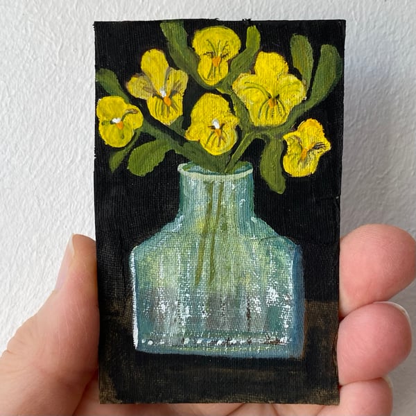 Image of yellow violas in an antique bottle