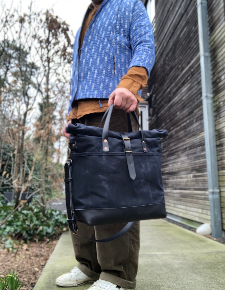 Image of Black waxed canvas carryall with luggage handle attachment leather handles and shoul