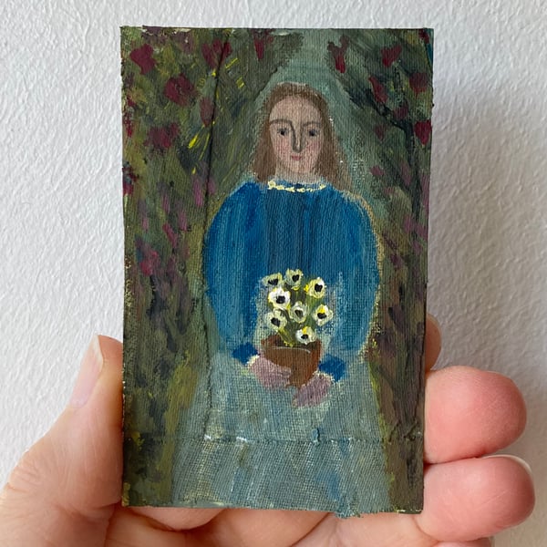 Image of woman in a shady garden with pot of flowers 