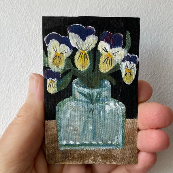 Image of purple and yellow violas in an antique bottle