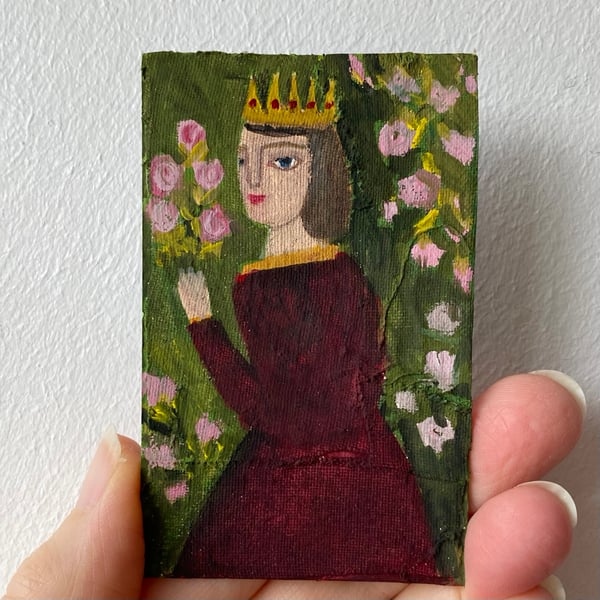 Image of queen in dark ruby gown with roses